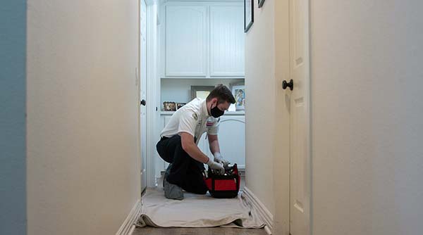 Looking For Artesia Air Conditioning Service? Look No Further Than Service Champions, Our Techs Are Committed To Keeping Your Home Clean With Drop Cloths, Just Like The Tech In This Photo.