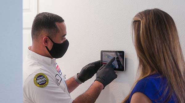 Image: A Service Champions Tech Shows A Client How To Use A Smart Thermostat. Service Champions Provides The Best Los Alamitos Ac Service.
