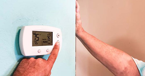 Image: A Man Adjusting His Thermostat.